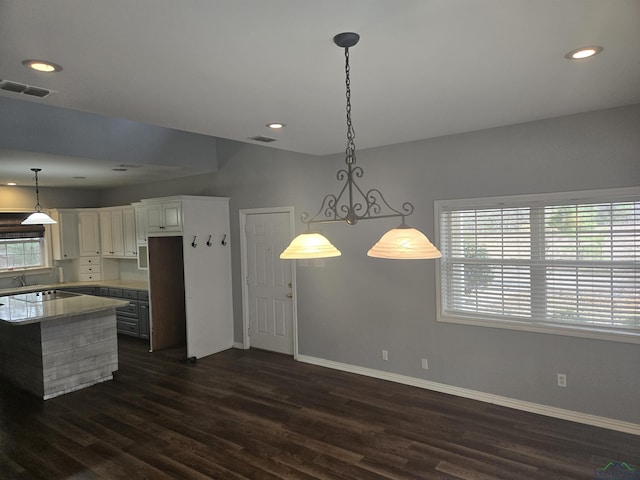 kitchen with dark hardwood / wood-style floors, decorative light fixtures, white cabinetry, light stone counters, and black electric cooktop