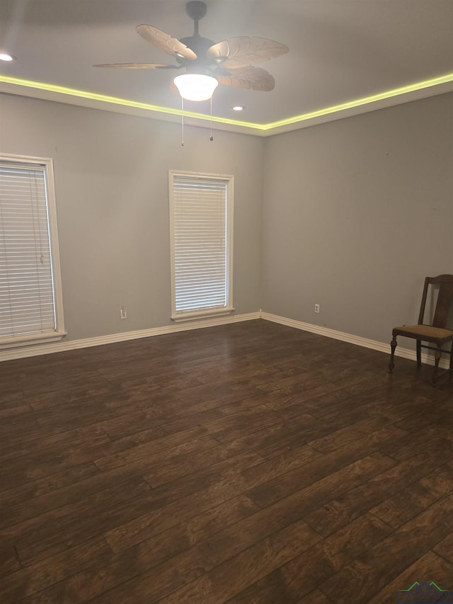 empty room with ceiling fan and dark hardwood / wood-style flooring