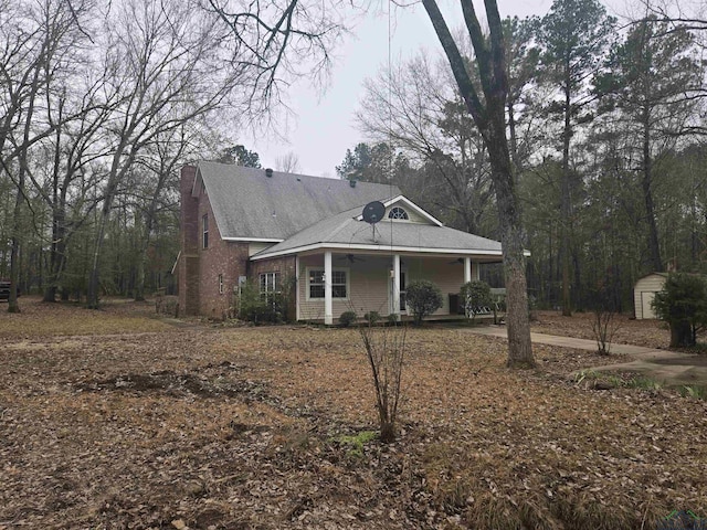 view of front of property featuring a porch and a storage shed