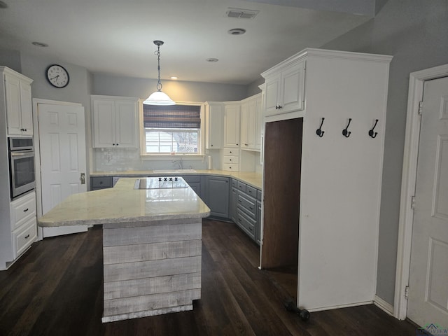 kitchen with white cabinetry, a center island, hanging light fixtures, black electric cooktop, and oven