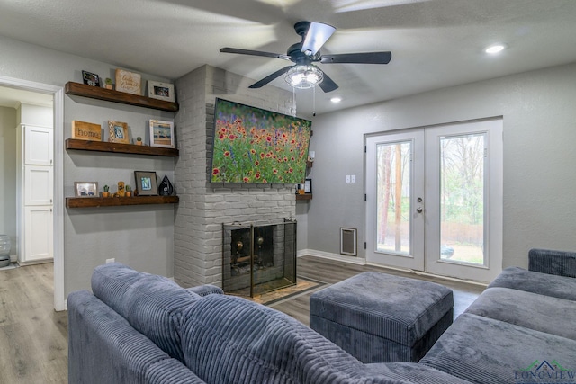 living area featuring recessed lighting, wood finished floors, baseboards, french doors, and a brick fireplace