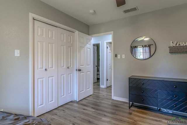 unfurnished bedroom with a closet, visible vents, ceiling fan, wood finished floors, and baseboards