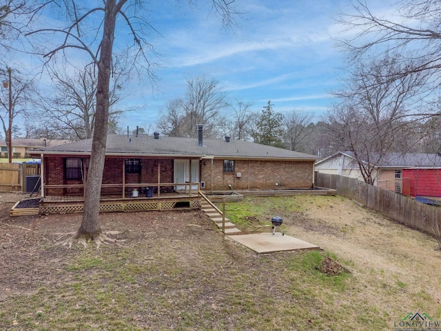 rear view of house with a deck, brick siding, and a fenced backyard