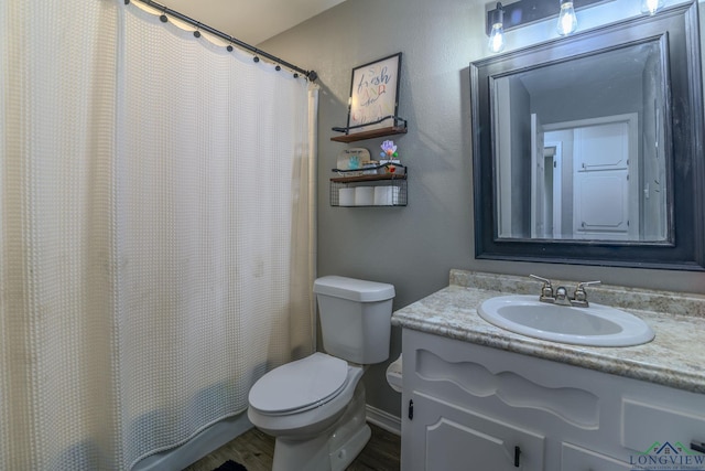 full bathroom with toilet, baseboards, wood finished floors, and vanity