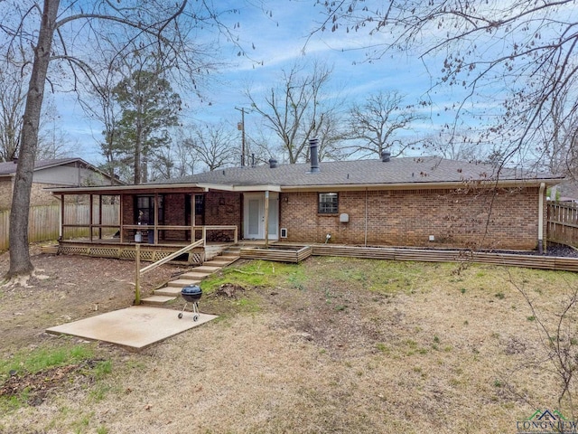 back of house featuring brick siding, fence, and a deck