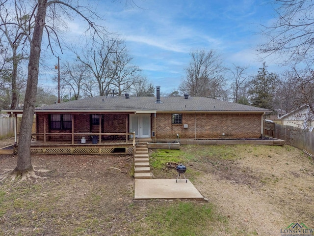 rear view of house featuring a deck, brick siding, and a fenced backyard