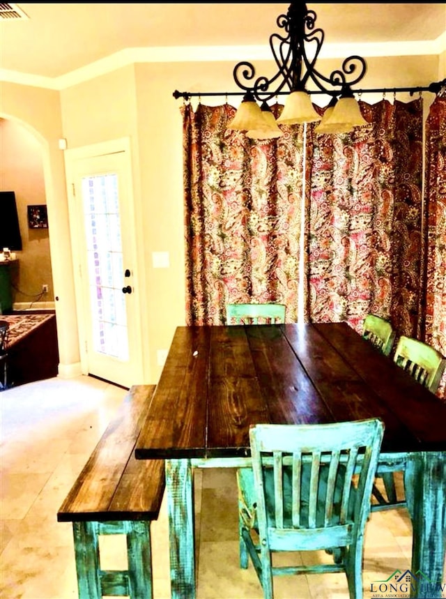 dining area with crown molding, visible vents, and arched walkways