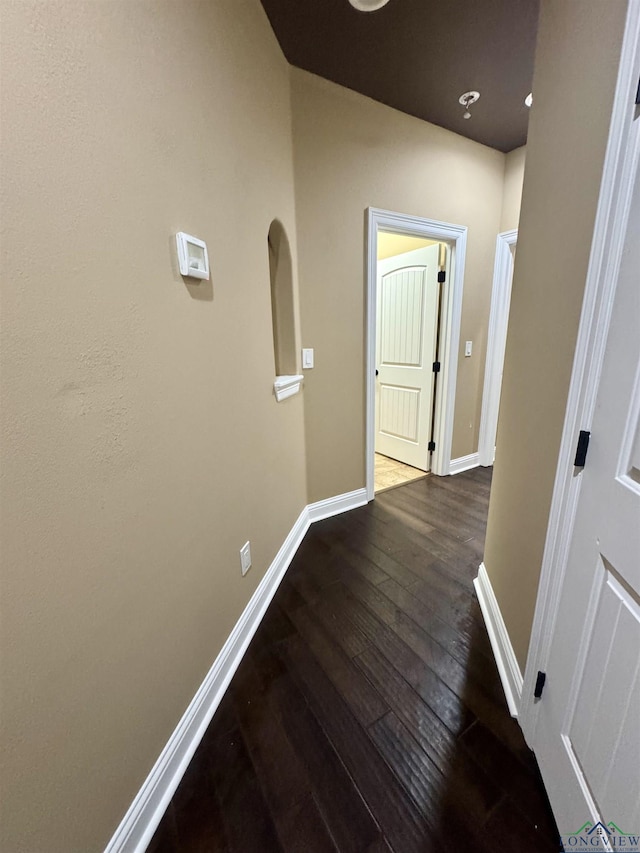 corridor with baseboards and wood-type flooring
