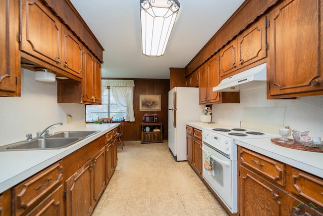 kitchen featuring sink, white appliances, and wood walls