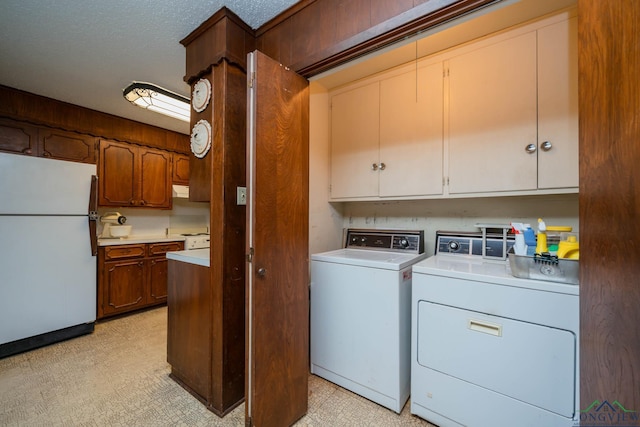 washroom with cabinets, washing machine and dryer, and a textured ceiling