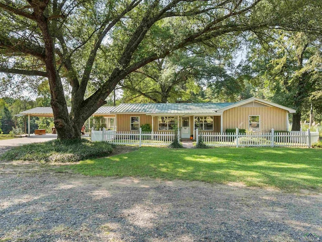 ranch-style house with driveway, a standing seam roof, a fenced front yard, and metal roof