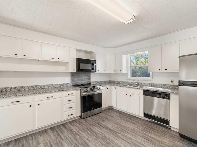 kitchen featuring appliances with stainless steel finishes, dark wood-type flooring, light stone countertops, white cabinets, and sink