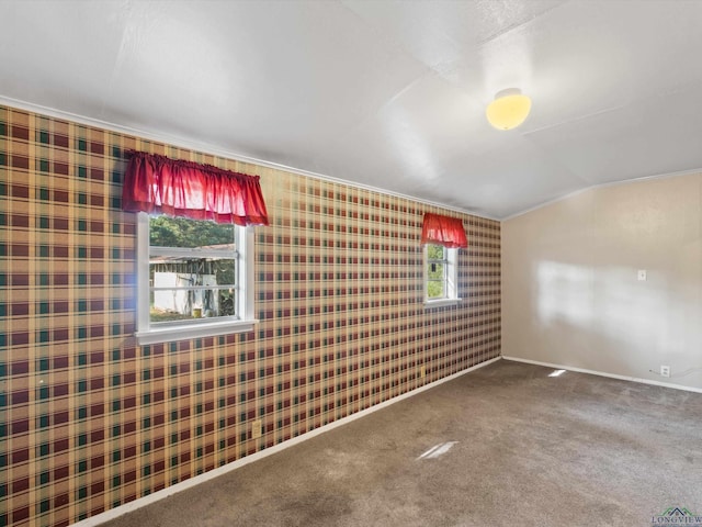 carpeted spare room with ornamental molding and lofted ceiling