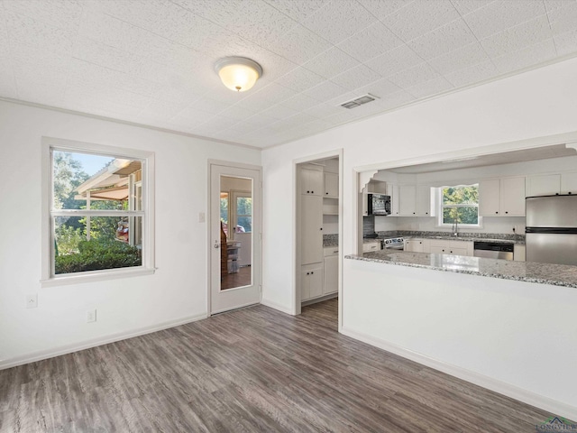 kitchen featuring dark wood-type flooring, white cabinetry, stainless steel appliances, and light stone countertops