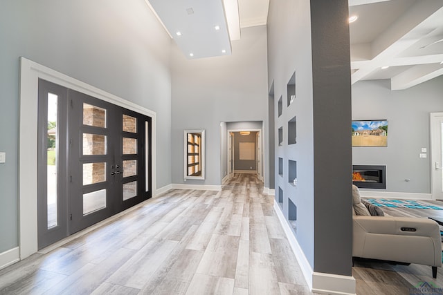 entrance foyer with french doors, a high ceiling, and light wood-type flooring