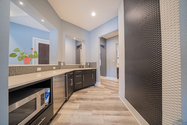 bar featuring sink, backsplash, and light hardwood / wood-style floors