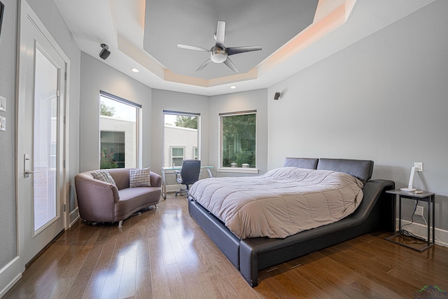 bedroom featuring dark wood-type flooring, ceiling fan, and a raised ceiling