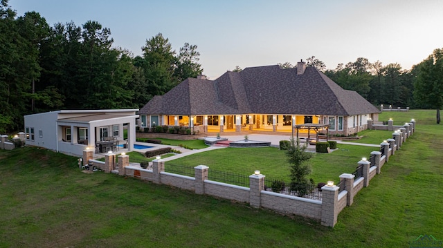 back house at dusk with a patio and a yard