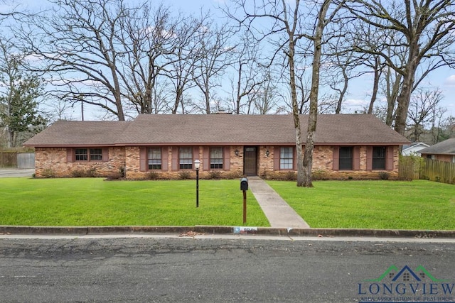 ranch-style home with a front lawn, a shingled roof, fence, and brick siding