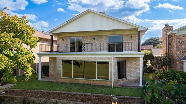 rear view of house with a balcony, a lawn, and a patio area