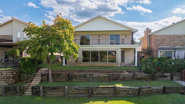 rear view of property featuring a balcony and a yard