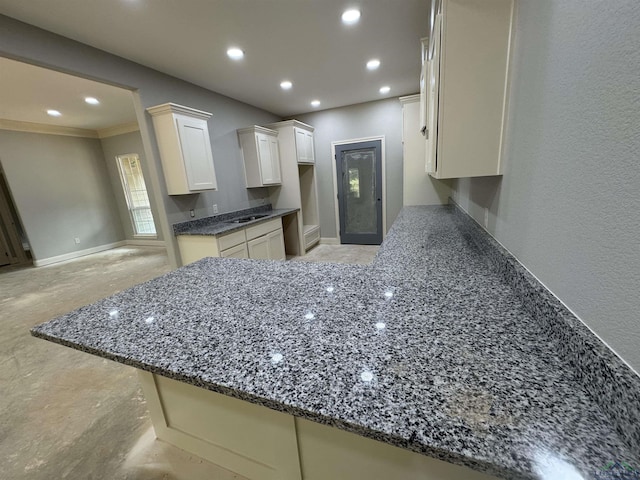 495 Lake Gladewater Rd, Gladewater, TX 75647 - kitchen featuring dark stone counters, a peninsula, recessed lighting, white cabinets, and ornamental molding