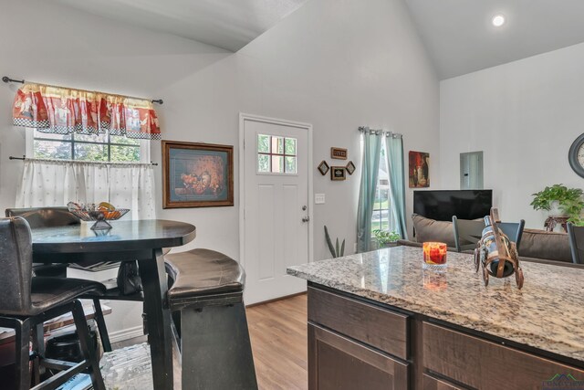 204 Hurley Ave, Gladewater, TX 75647 - kitchen featuring electric panel, dark brown cabinets, light stone countertops, light wood-style floors, and high vaulted ceiling