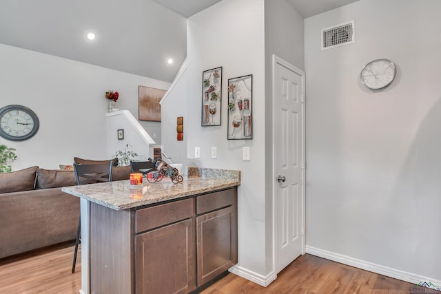 204 Hurley Ave, Gladewater, TX 75647 - kitchen featuring a breakfast bar, light wood-type flooring, baseboards, light stone countertops, and visible vents