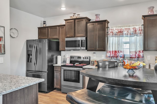 204 Hurley Ave, Gladewater, TX 75647 - kitchen with light stone counters, recessed lighting, dark brown cabinets, stainless steel appliances, and light wood finished floors