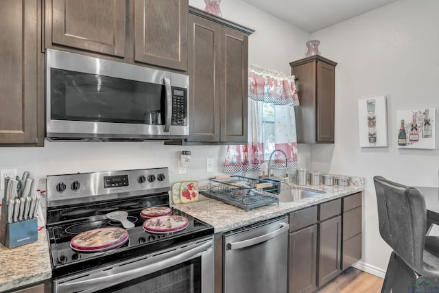 204 Hurley Ave, Gladewater, TX 75647 - kitchen featuring appliances with stainless steel finishes, a sink, light stone counters, and dark brown cabinetry