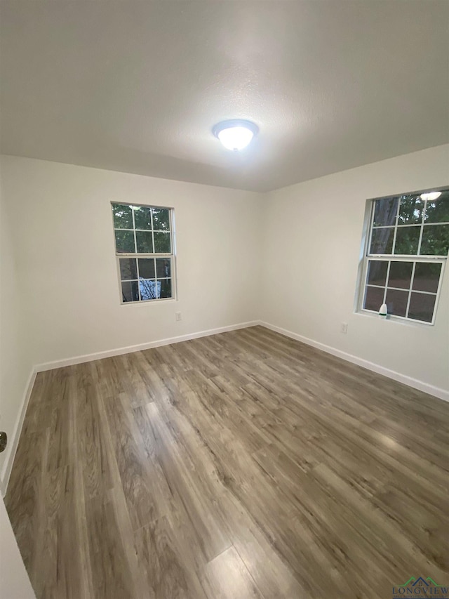 unfurnished room featuring dark wood-style floors, a textured ceiling, and baseboards