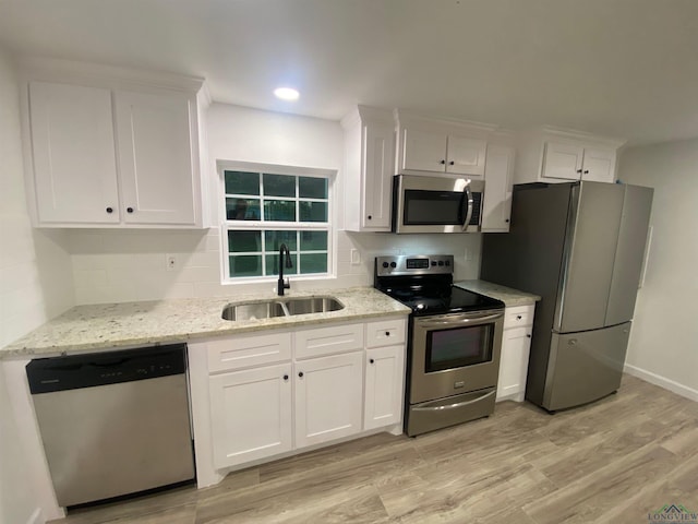 kitchen with appliances with stainless steel finishes, backsplash, a sink, and white cabinets