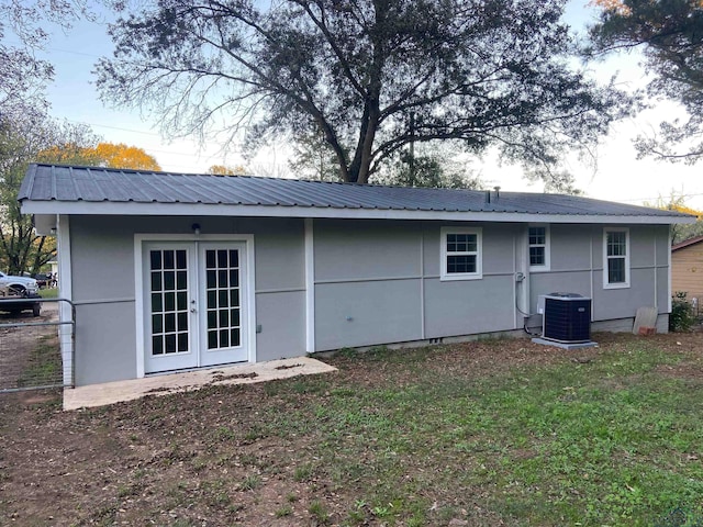 rear view of house with a yard, metal roof, french doors, and central AC unit