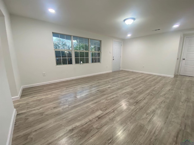 unfurnished room with recessed lighting, wood finished floors, visible vents, and baseboards