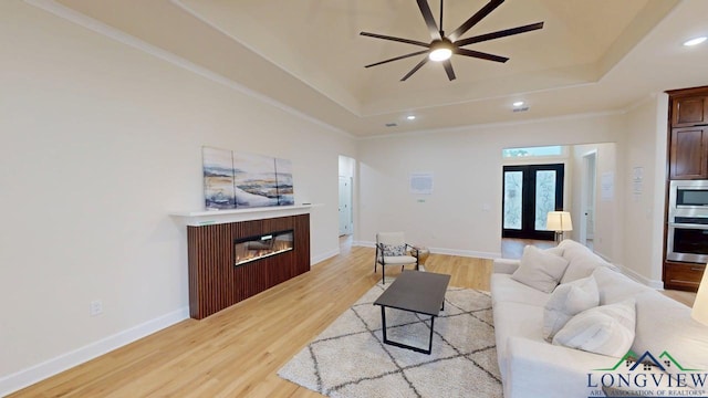2509 Windmill Ln, Longview, TX 75601 - living room featuring a tray ceiling, a ceiling fan, recessed lighting, light wood-style floors, and a glass covered fireplace