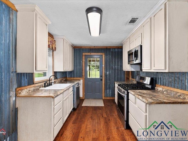 kitchen featuring white cabinets, sink, a healthy amount of sunlight, dark hardwood / wood-style flooring, and stainless steel appliances