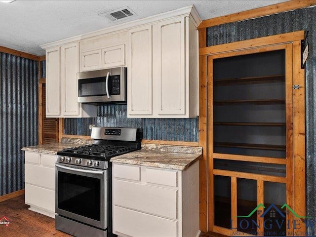 kitchen with white cabinetry, light stone countertops, dark hardwood / wood-style flooring, and appliances with stainless steel finishes