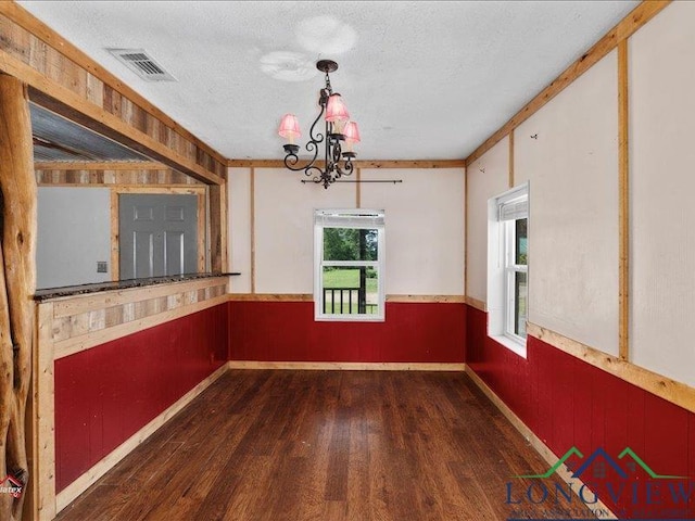 spare room with dark hardwood / wood-style floors, crown molding, a textured ceiling, and an inviting chandelier