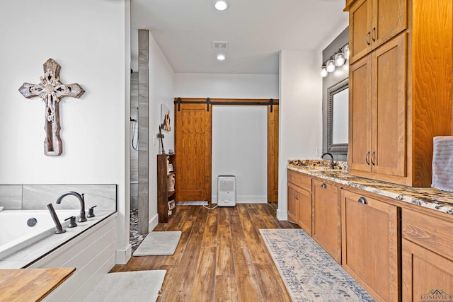 full bathroom with visible vents, a shower stall, vanity, wood finished floors, and a garden tub