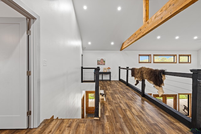 corridor featuring beam ceiling, an upstairs landing, plenty of natural light, and wood finished floors