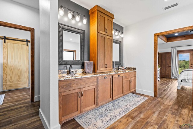 bathroom featuring visible vents, baseboards, a sink, and wood finished floors