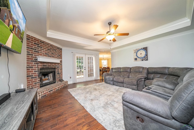 1505 Leach St, Kilgore, TX 75662 - living area featuring a tray ceiling, dark wood finished floors, a brick fireplace, crown molding, and a ceiling fan