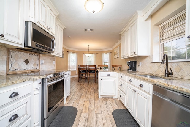 1505 Leach St, Kilgore, TX 75662 - kitchen with stainless steel appliances, a sink, light wood-style flooring, light stone counters, and ornamental molding
