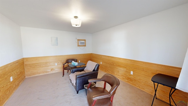 living area with light carpet and wooden walls