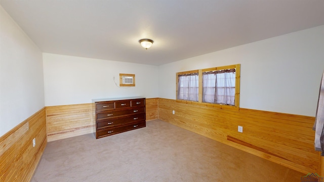 unfurnished bedroom featuring light colored carpet and wood walls