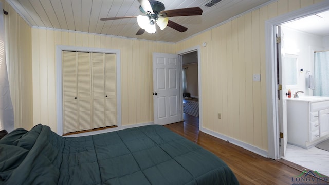 bedroom featuring ensuite bathroom, sink, ceiling fan, wood-type flooring, and a closet