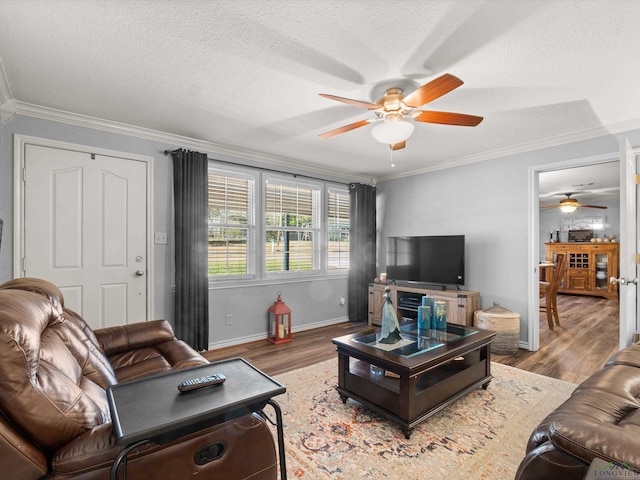 living area with baseboards, ceiling fan, wood finished floors, crown molding, and a textured ceiling