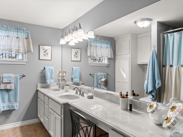 bathroom with double vanity, tile patterned flooring, baseboards, and a sink