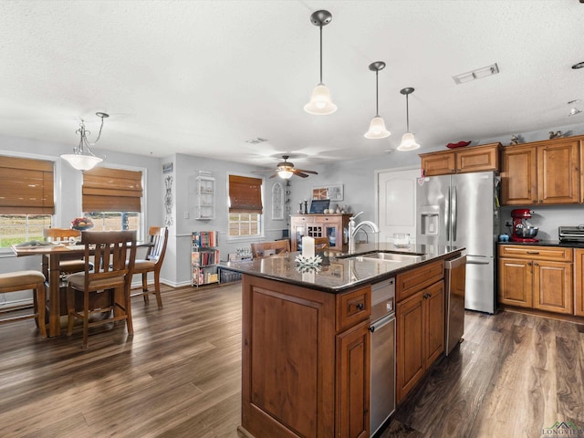 kitchen featuring dark wood-style floors, stainless steel fridge, brown cabinets, and a sink