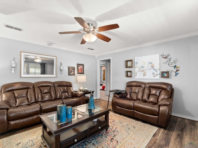 living area with a ceiling fan, wood finished floors, visible vents, and crown molding